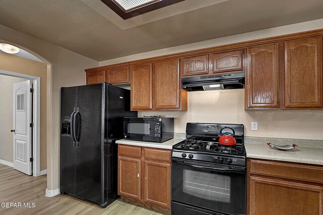 7101 Luz De Sol Dr, El Paso, TX 79912 - kitchen featuring baseboards, light countertops, light wood-type flooring, under cabinet range hood, and black appliances