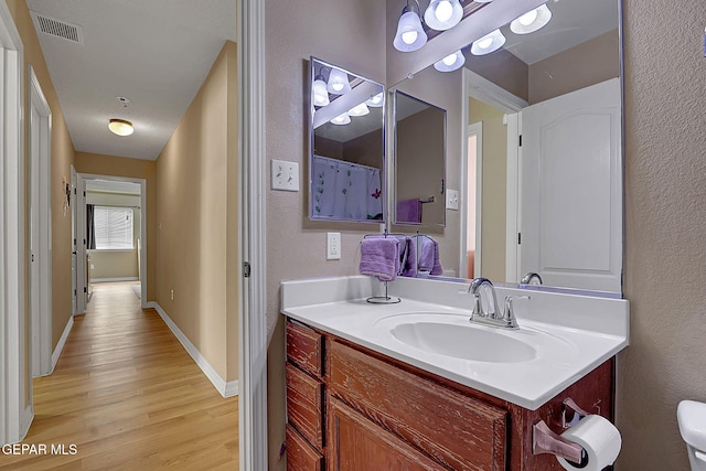 7101 Luz De Sol Dr, El Paso, TX 79912 - bathroom featuring vanity, baseboards, toilet, visible vents, and wood finished floors