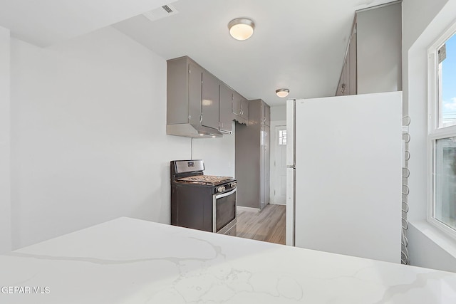 bedroom featuring light wood-style flooring, visible vents, and freestanding refrigerator