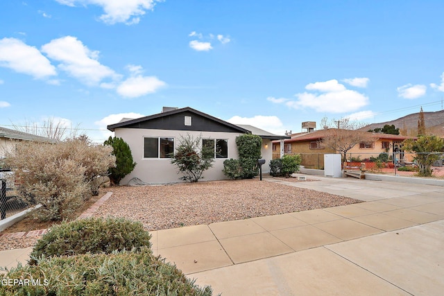 ranch-style house featuring stucco siding and fence