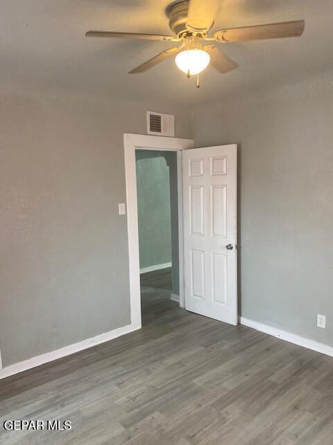 spare room with baseboards, ceiling fan, visible vents, and wood finished floors