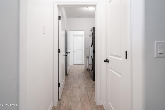 hall featuring stacked washing maching and dryer and wood finish floors
