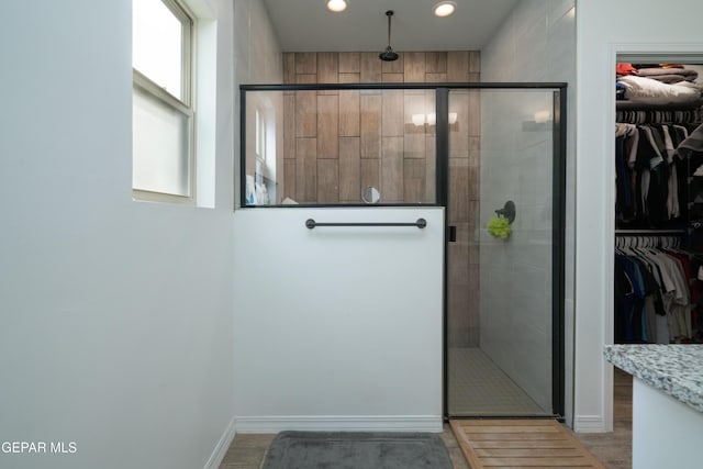 bathroom with recessed lighting, a walk in closet, and a stall shower
