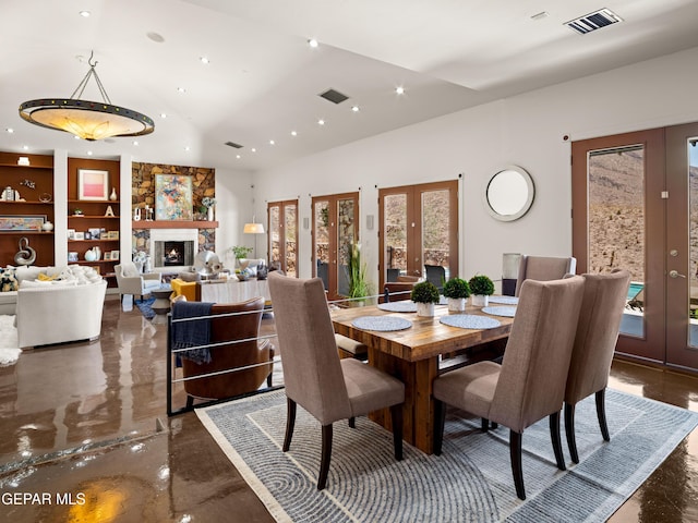 dining space with visible vents, a stone fireplace, recessed lighting, built in shelves, and french doors