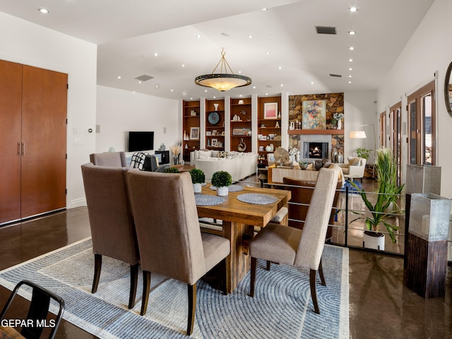 dining space featuring visible vents, recessed lighting, concrete flooring, and a stone fireplace