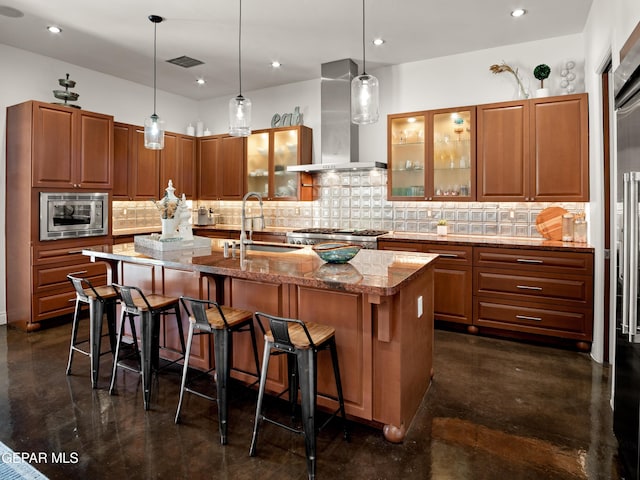 kitchen featuring a sink, wall chimney exhaust hood, a kitchen breakfast bar, and a kitchen island with sink