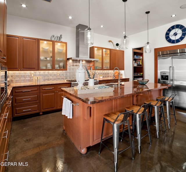 kitchen featuring a sink, extractor fan, concrete floors, built in fridge, and backsplash