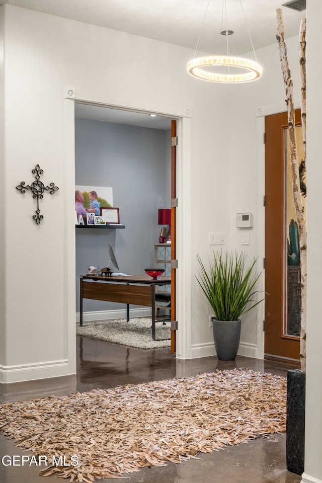 corridor featuring baseboards and a notable chandelier