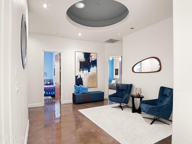 sitting room featuring a raised ceiling, finished concrete flooring, recessed lighting, baseboards, and visible vents