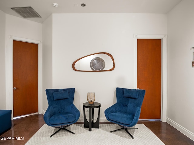 living area with baseboards, visible vents, and finished concrete floors