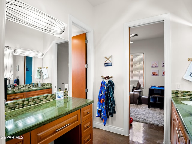 bathroom featuring vanity, concrete flooring, baseboards, and tasteful backsplash