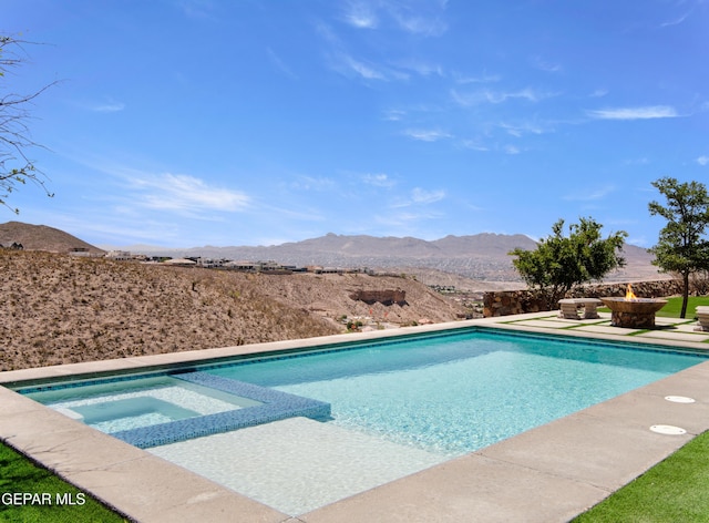 view of pool featuring a pool with connected hot tub, a fire pit, a mountain view, and a patio area