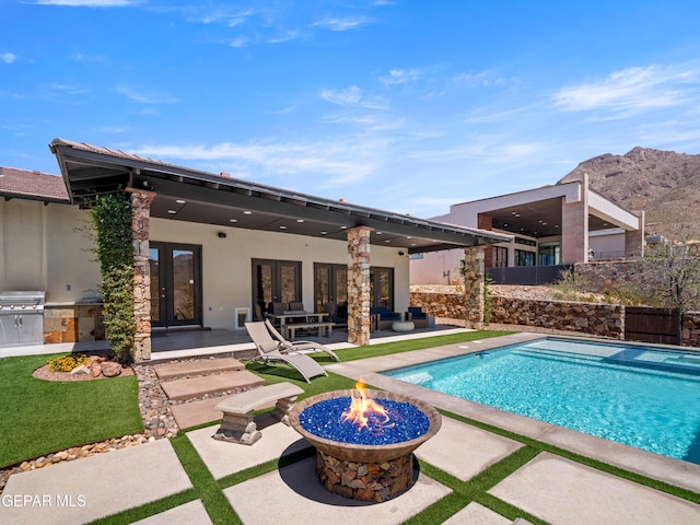 view of pool with french doors, a patio area, a fenced in pool, fence, and an outdoor kitchen