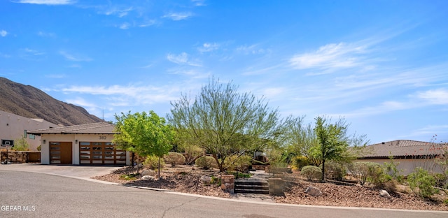 exterior space featuring concrete driveway, an attached garage, and a mountain view