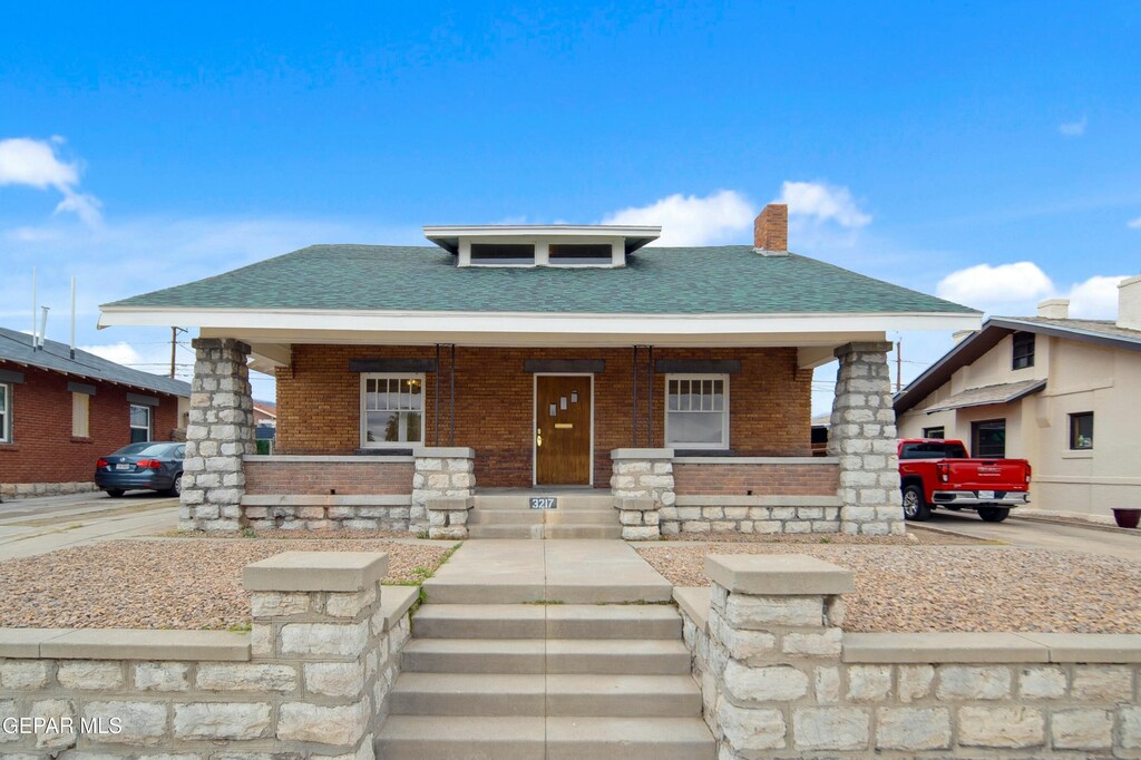 3217 Aurora Ave, El Paso, TX 79930 - view of front of house with covered porch, brick siding, a chimney, and roof with shingles