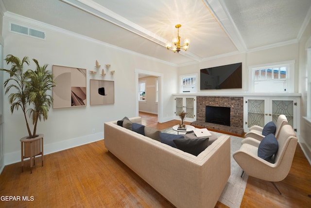 3217 Aurora Ave, El Paso, TX 79930 - living room featuring a chandelier, a brick fireplace, wood finished floors, baseboards, and crown molding