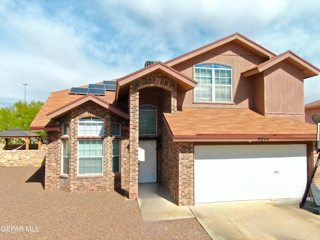 view of front of property featuring concrete driveway, a garage, and solar panels