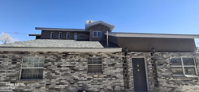 view of front of house with roof with shingles and brick siding