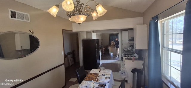 kitchen featuring freestanding refrigerator, white cabinets, vaulted ceiling, a chandelier, and visible vents