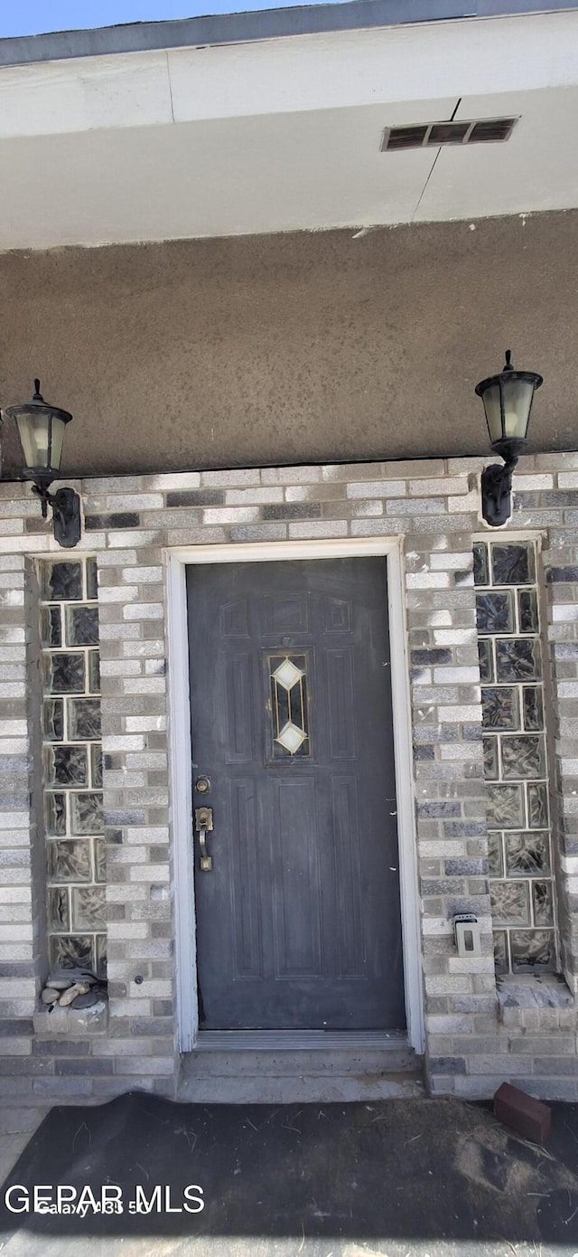 entrance to property with visible vents and brick siding
