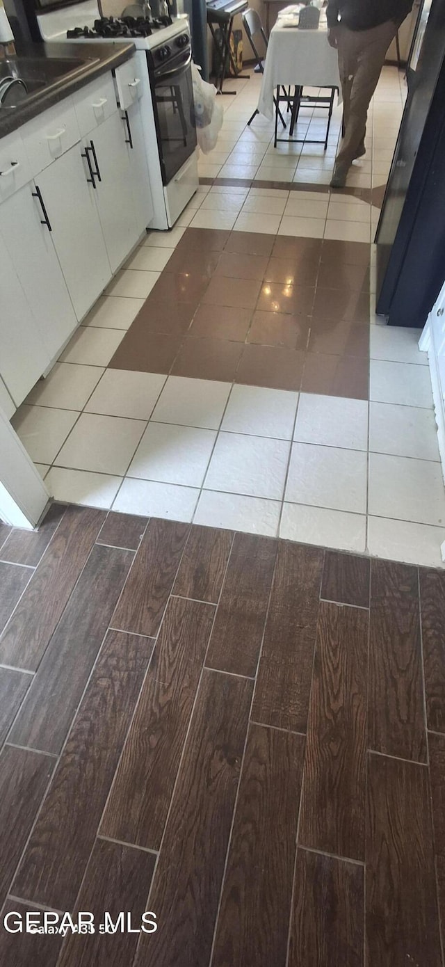 details featuring wood tiled floor, dark countertops, white cabinets, and gas range gas stove