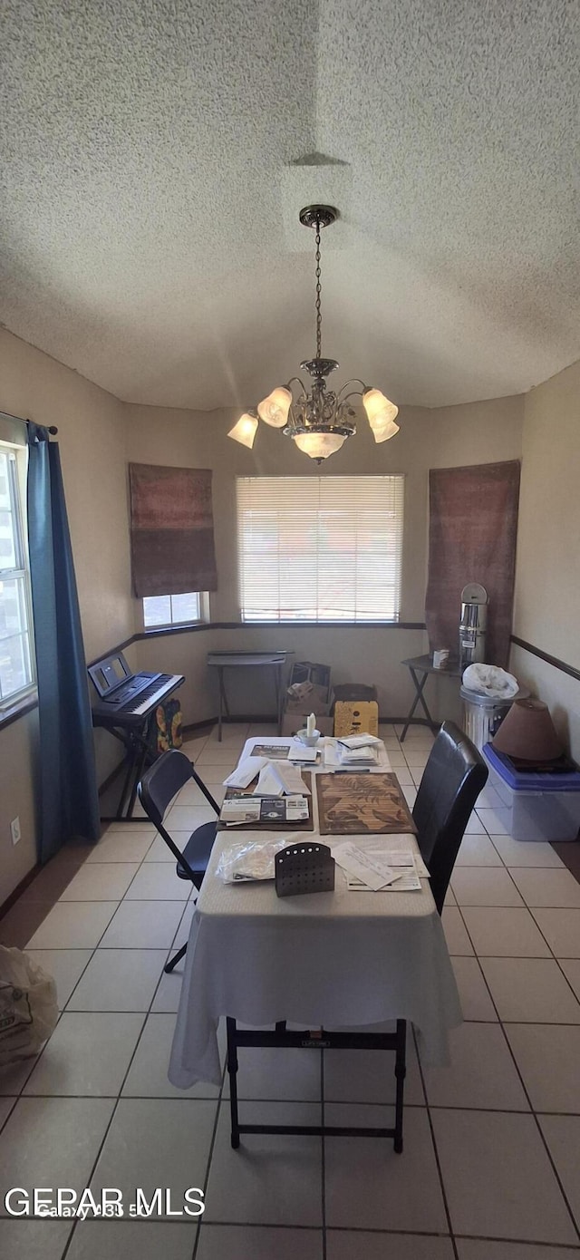 dining area featuring light tile patterned floors, a chandelier, and a textured ceiling