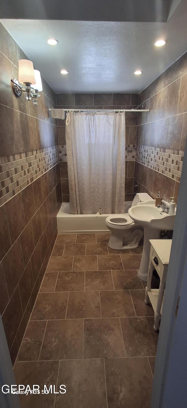 bathroom with toilet, tiled shower / bath, recessed lighting, and tile walls