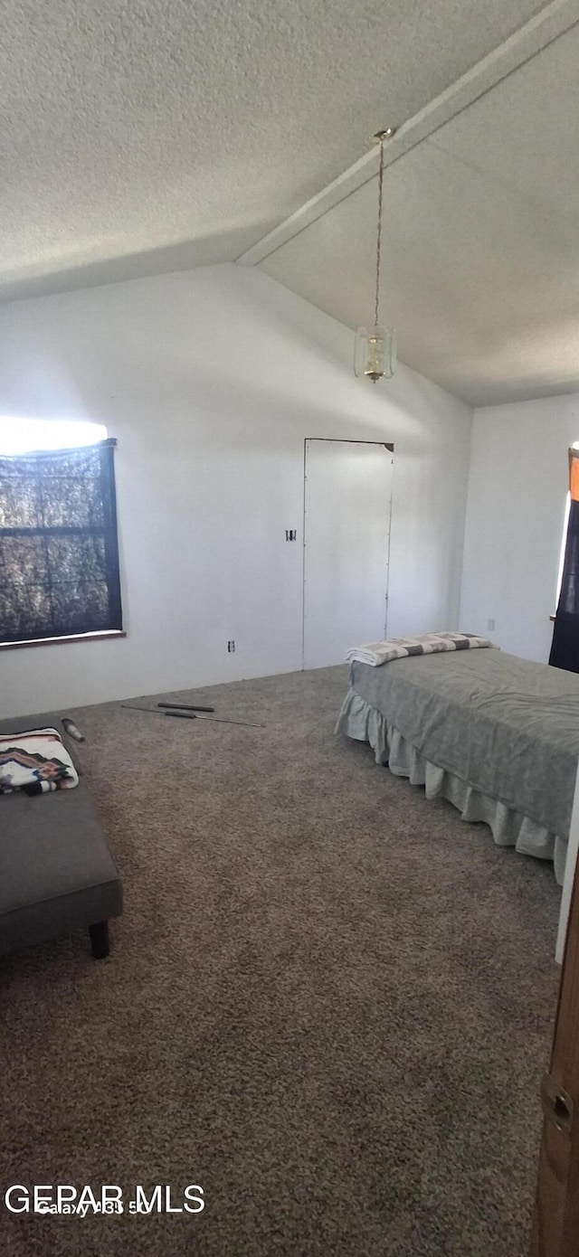 unfurnished bedroom with a textured ceiling, carpet flooring, and lofted ceiling with beams