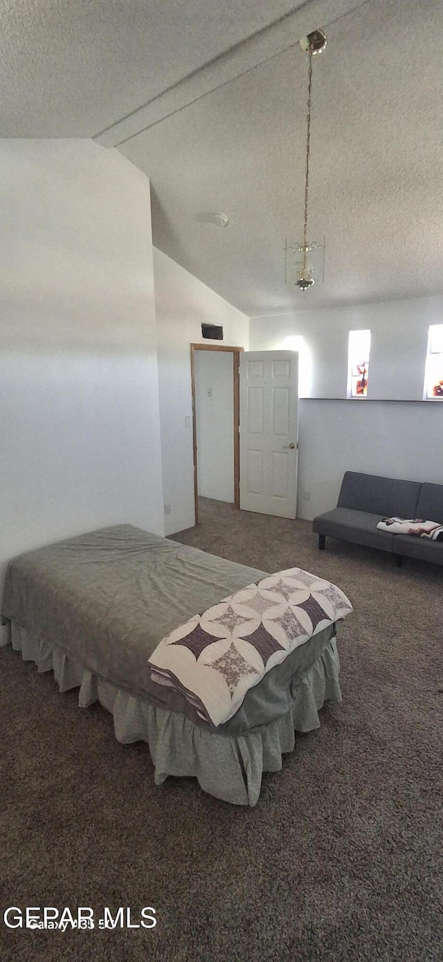 carpeted bedroom featuring a textured ceiling and vaulted ceiling