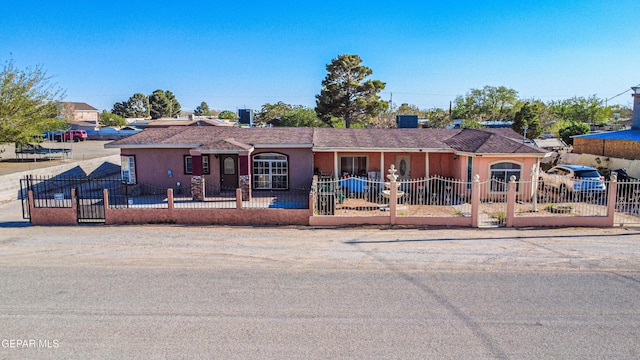ranch-style home featuring a fenced front yard and stucco siding