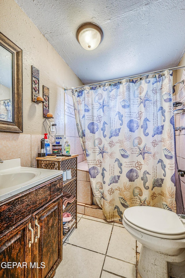 full bath with a textured ceiling, vanity, tile patterned flooring, toilet, and a textured wall