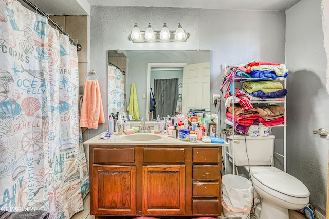 bathroom featuring toilet, a shower with shower curtain, vanity, and a textured wall