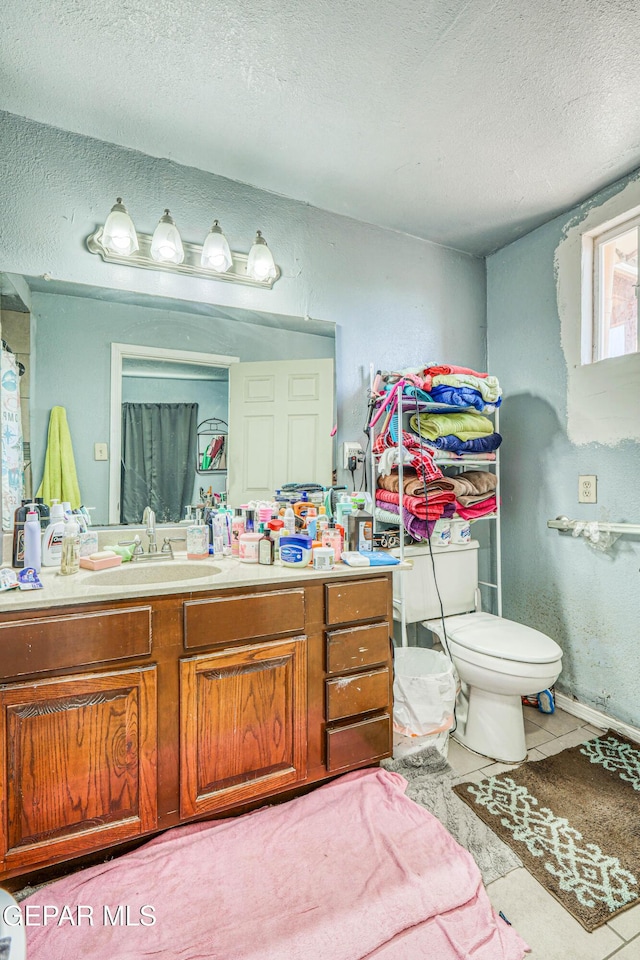 bathroom with toilet, a textured wall, a textured ceiling, vanity, and tile patterned floors