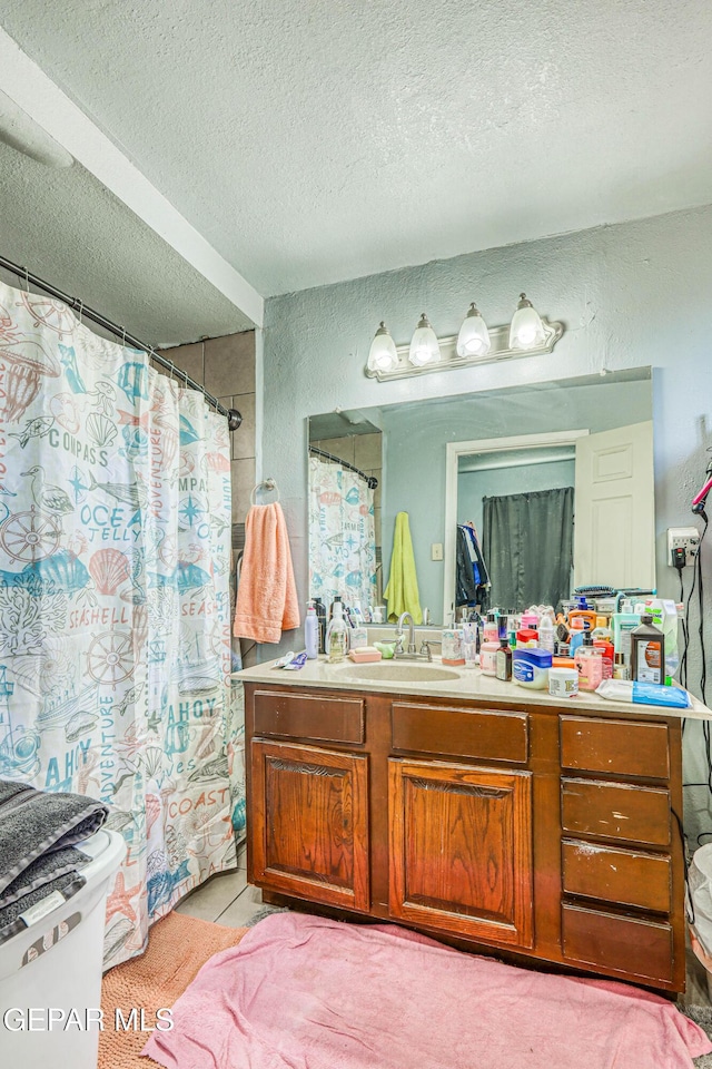 full bathroom with a shower with curtain, vanity, a textured wall, and a textured ceiling