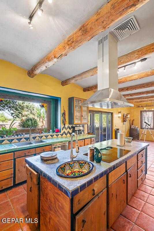 32 Cielo Dorado Dr, Anthony, NM 88021 - kitchen with black electric cooktop, a sink, tile counters, beam ceiling, and island exhaust hood