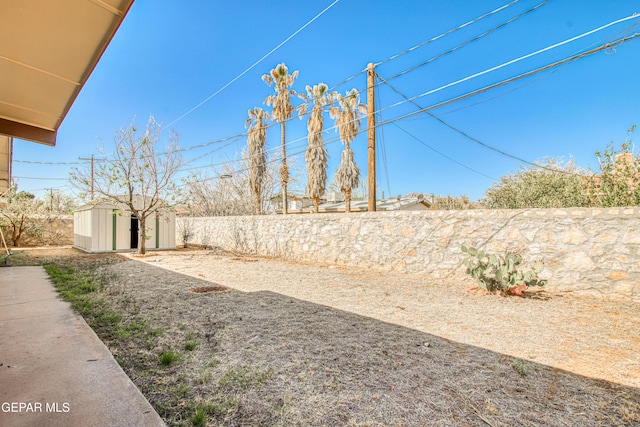 view of yard featuring a storage shed, a fenced backyard, and an outbuilding