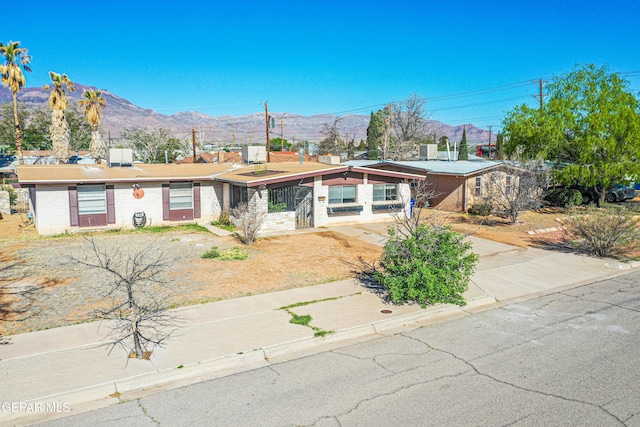 view of front of house featuring central AC unit, a mountain view, and driveway