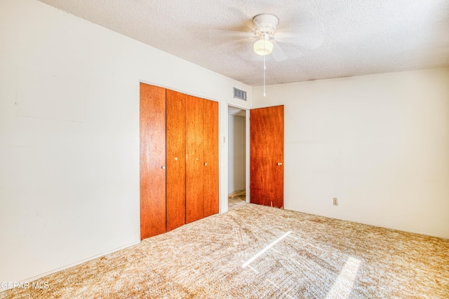 unfurnished bedroom featuring visible vents, a textured ceiling, carpet flooring, and a closet