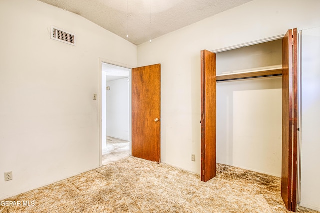 unfurnished bedroom with a textured ceiling, a closet, carpet, and visible vents