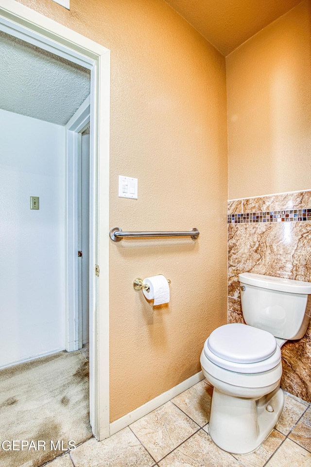 bathroom with toilet, tile patterned floors, and a textured ceiling