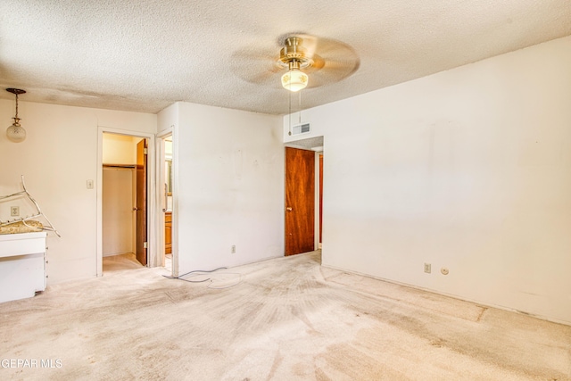 spare room featuring visible vents, ceiling fan, light colored carpet, and a textured ceiling