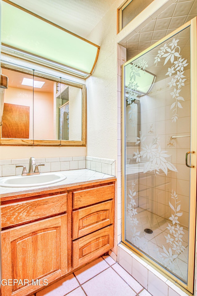 bathroom featuring tile patterned floors, a shower stall, and vanity