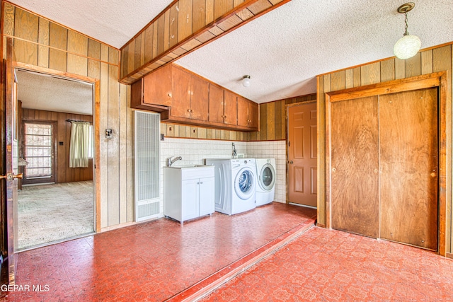 laundry room featuring washer and clothes dryer, wooden walls, a textured ceiling, and cabinet space
