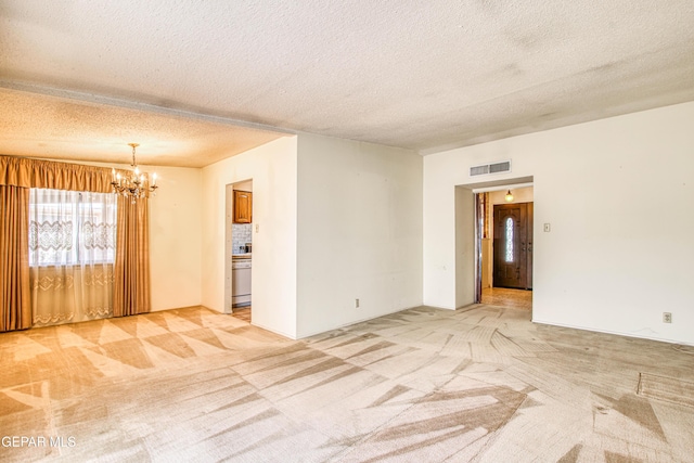 unfurnished room with light carpet, a notable chandelier, visible vents, and a textured ceiling