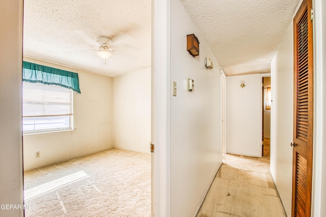 corridor with light carpet and a textured ceiling