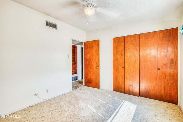 unfurnished bedroom with a closet, a textured ceiling, visible vents, ceiling fan, and carpet