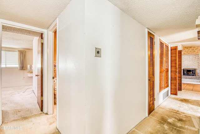 corridor with a textured ceiling and carpet floors
