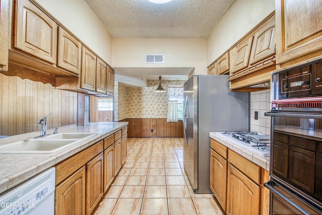 kitchen featuring tile countertops, white appliances, a textured ceiling, visible vents, and a sink