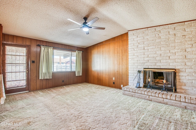 unfurnished living room with a fireplace, wooden walls, a textured ceiling, and a ceiling fan
