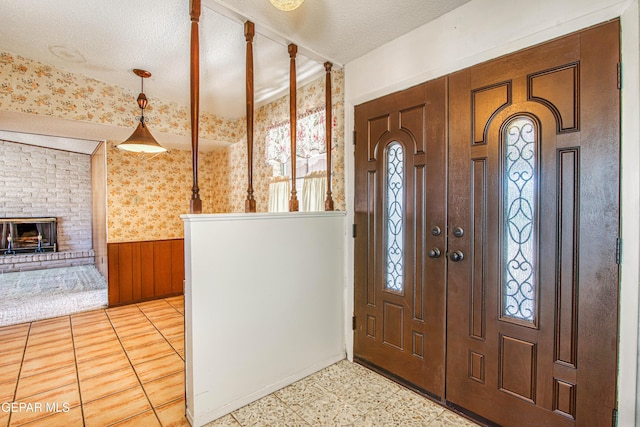 entryway featuring a wainscoted wall, a textured ceiling, a wealth of natural light, and wallpapered walls
